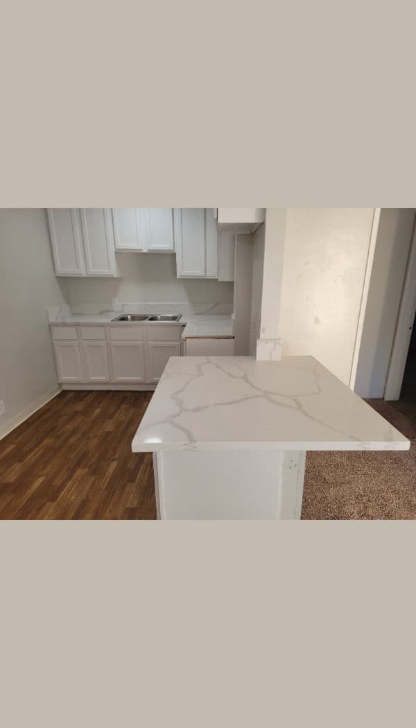 Modern kitchen with white cabinetry, marble countertop, and hardwood flooring.