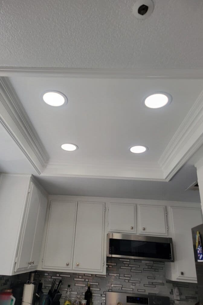 Modern kitchen ceiling with recessed LED lights and white cabinetry.