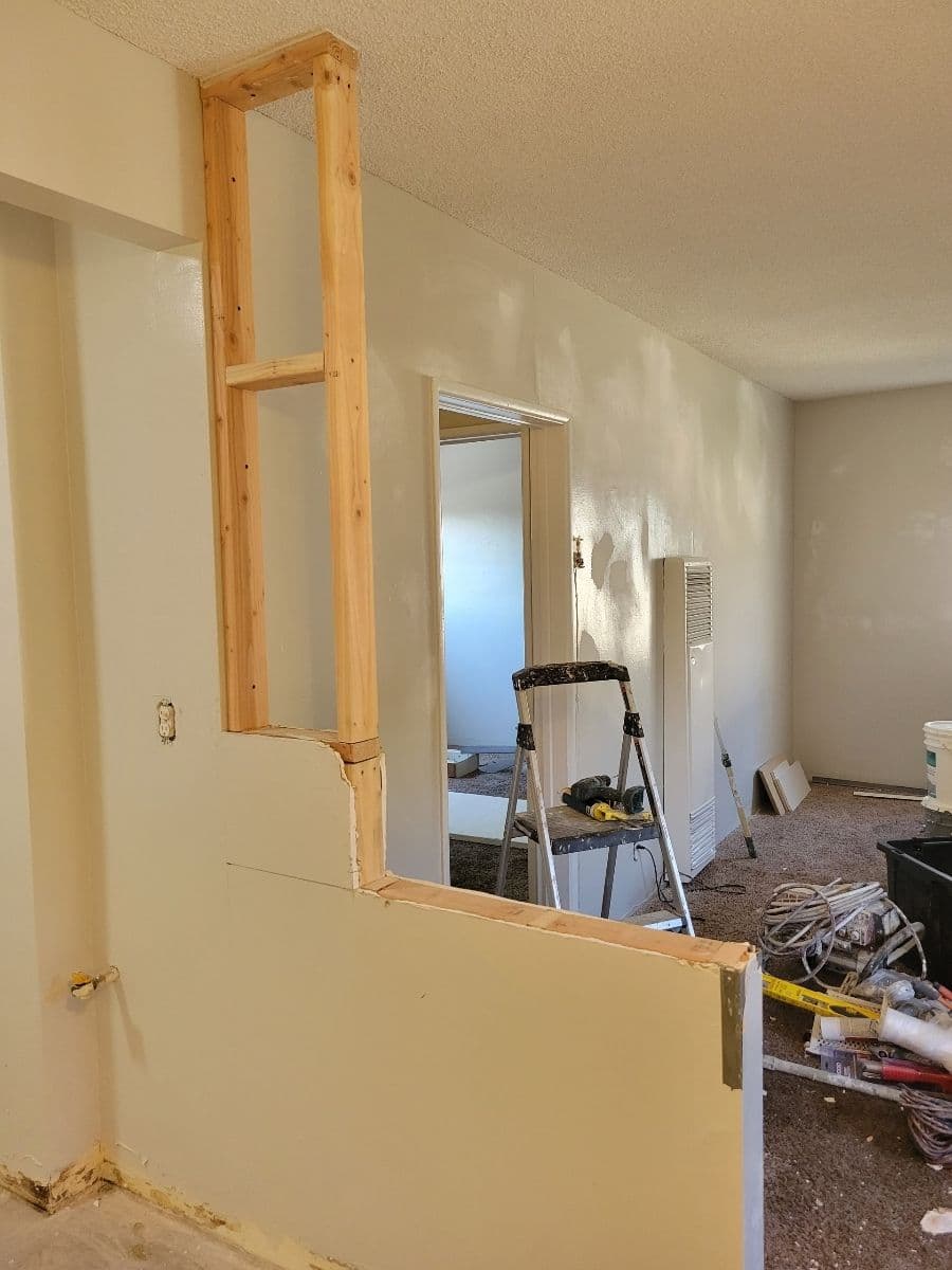 Home renovation in progress: framed opening in wall with tools and materials nearby.