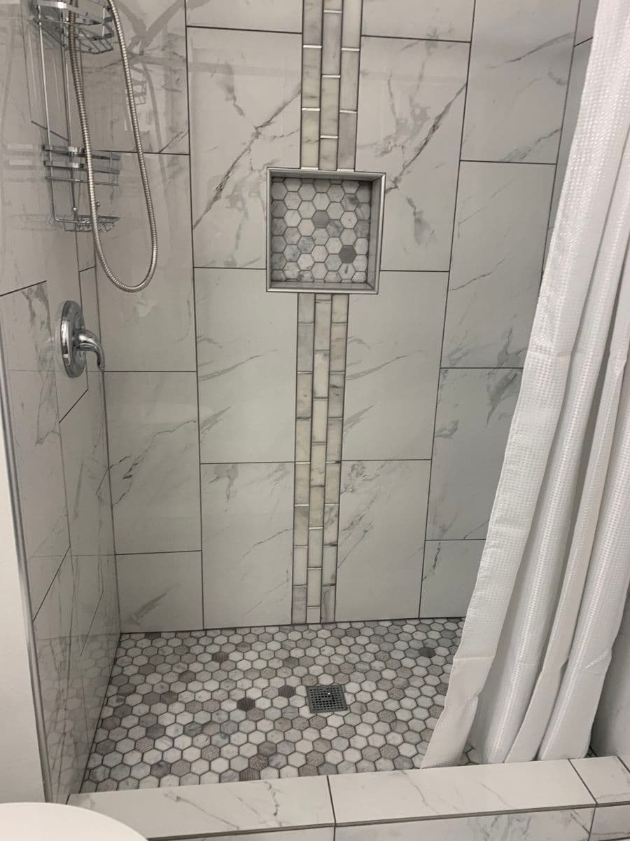Modern shower with marble tiles, hexagon floor, and glass shower enclosure. Elegant design.