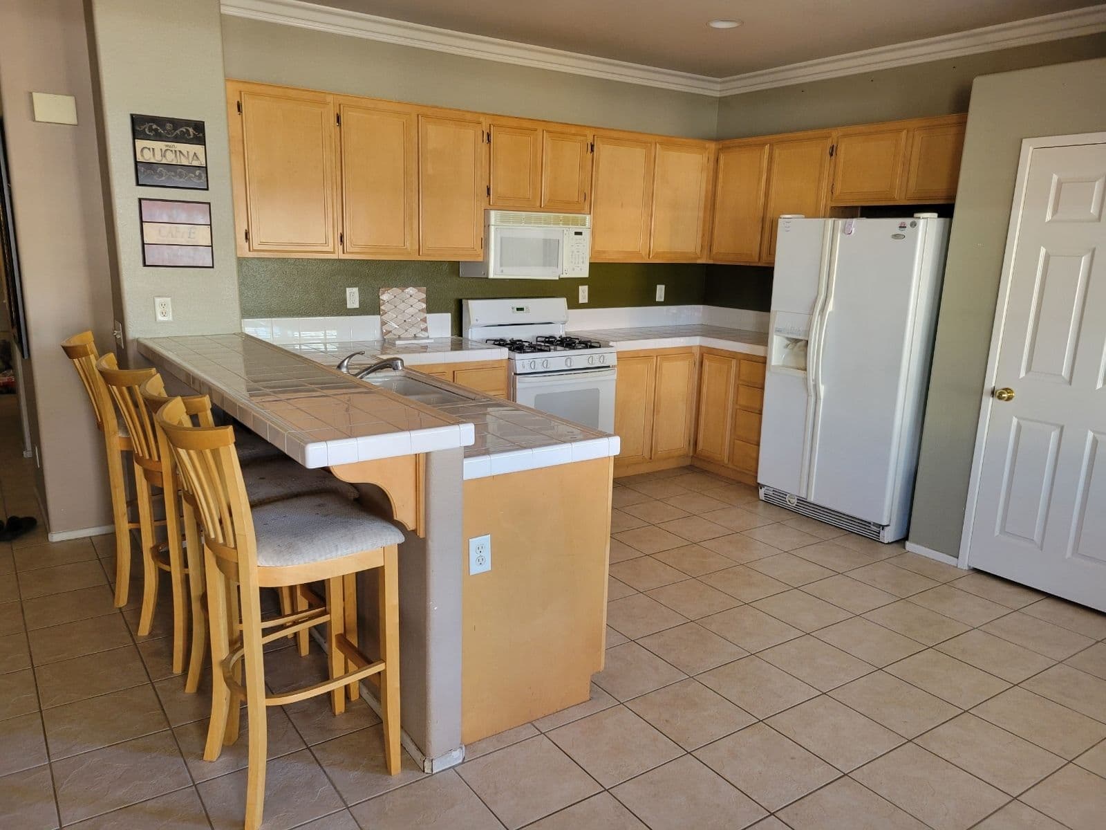 Modern kitchen with wooden cabinets, white appliances, and a breakfast bar with seating.