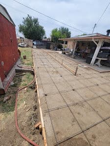 Concrete slab preparation for a new patio with rebar framework in a residential backyard.