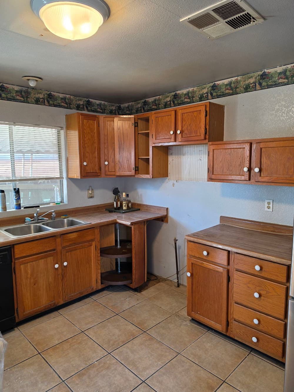 Spacious kitchen with wooden cabinets, tile flooring, and natural light from windows.